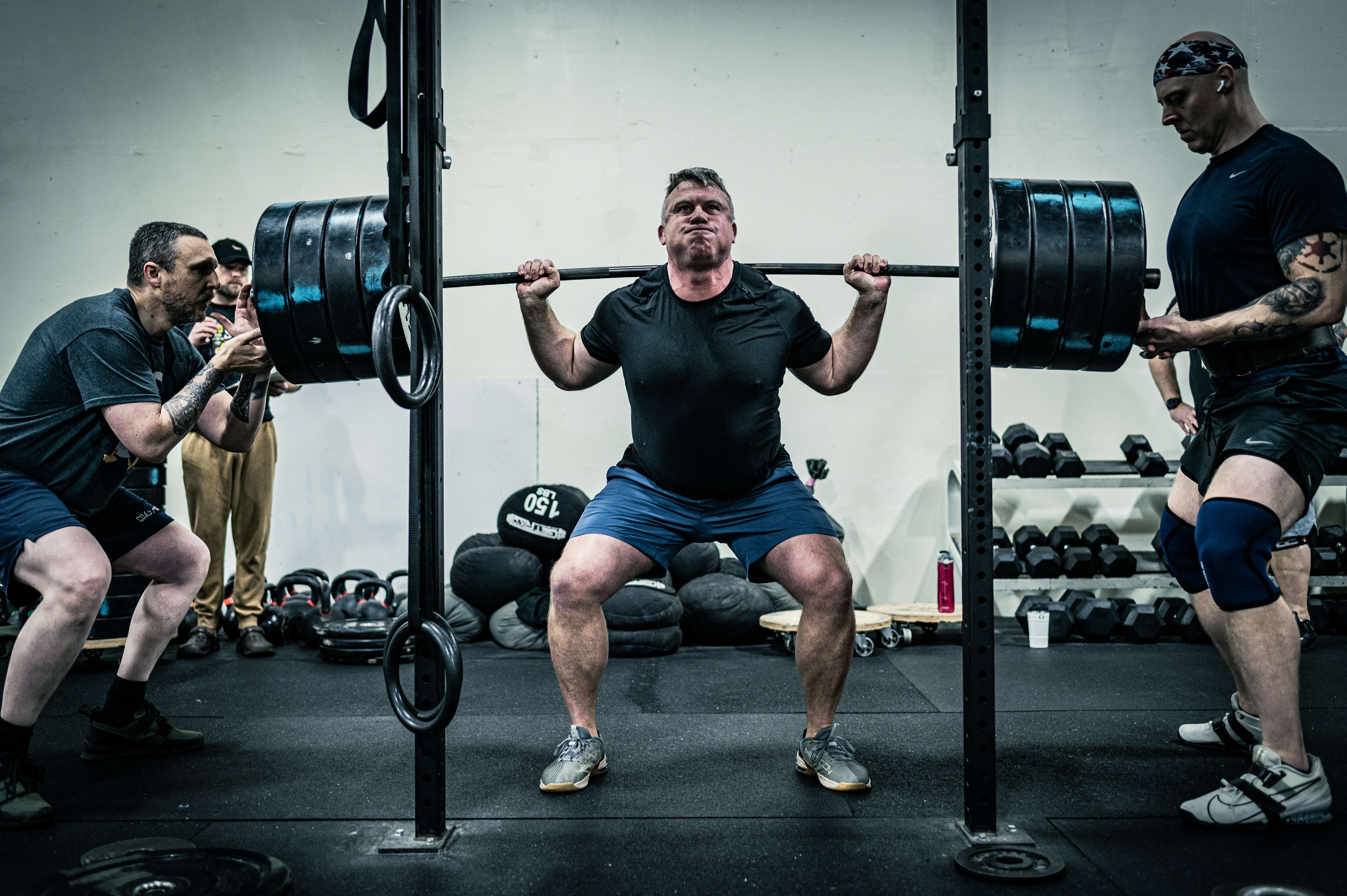 Athlete squatting heavy weight with community support at CrossFit Tigard