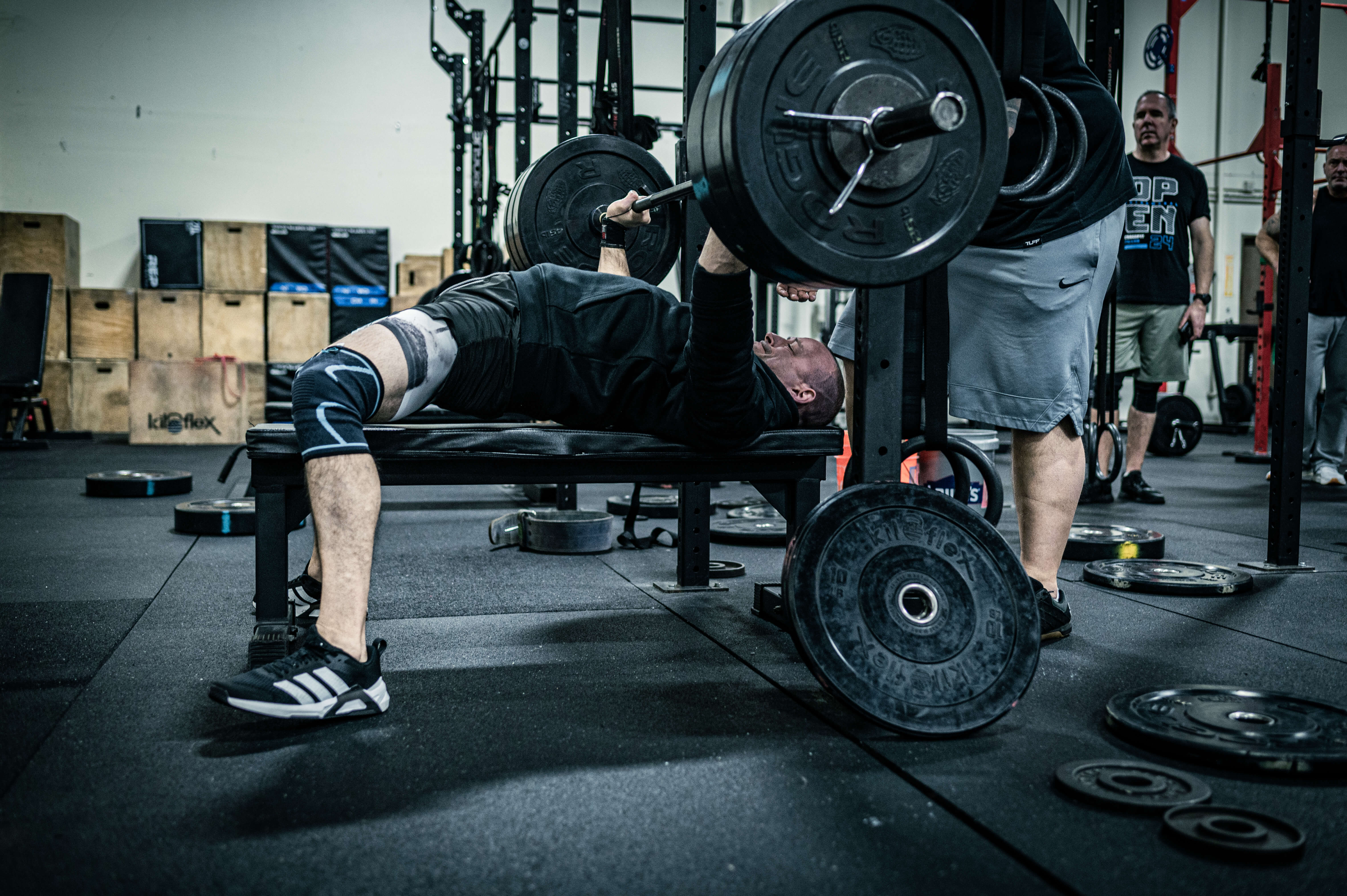 Athlete bench pressing heavy weight with spotter at CrossFit Tigard